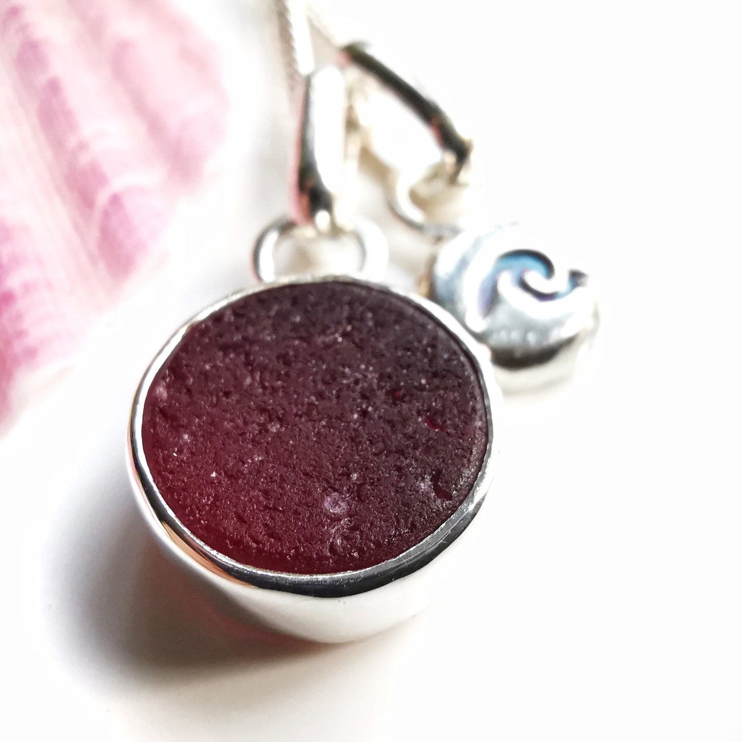 Scottish burgundy red sea glass and wave pebble duo of sterling silver pendants.