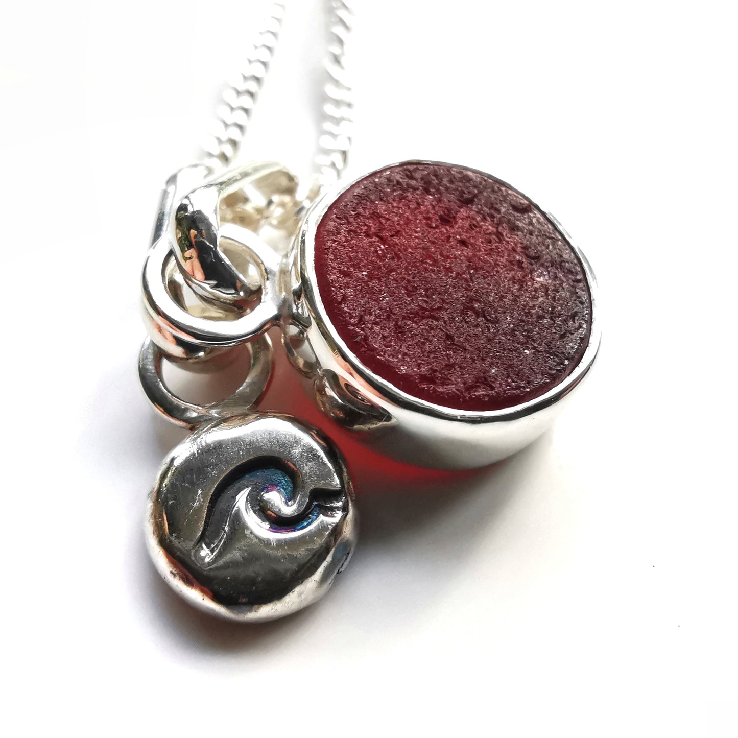 Scottish burgundy red sea glass and wave pebble duo of sterling silver pendants.