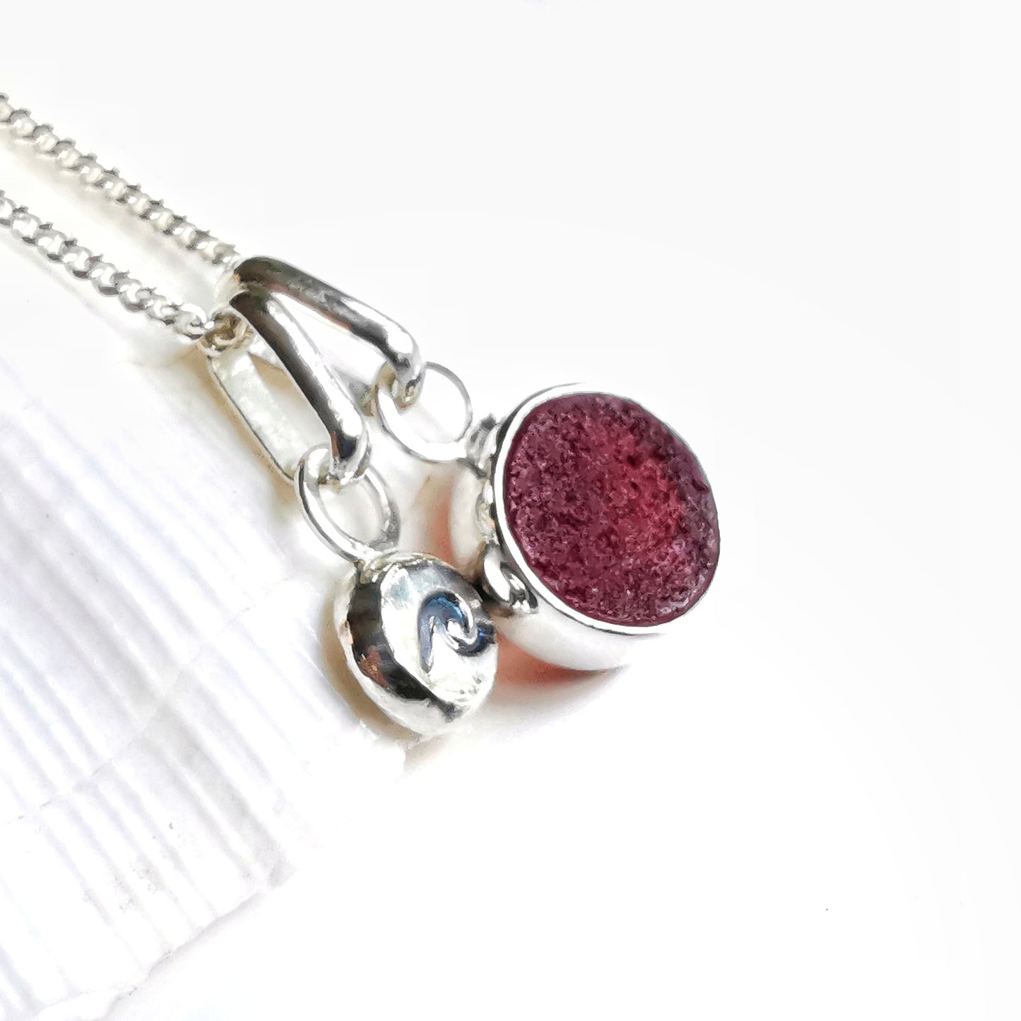 Scottish burgundy red sea glass and wave pebble duo of sterling silver pendants.