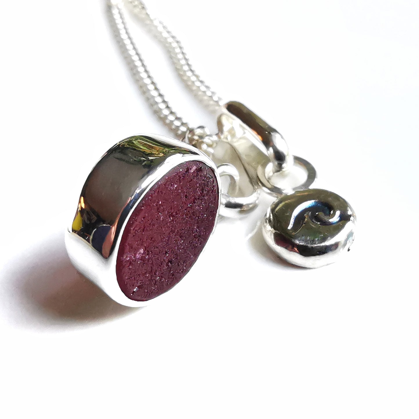Scottish burgundy red sea glass and wave pebble duo of sterling silver pendants.