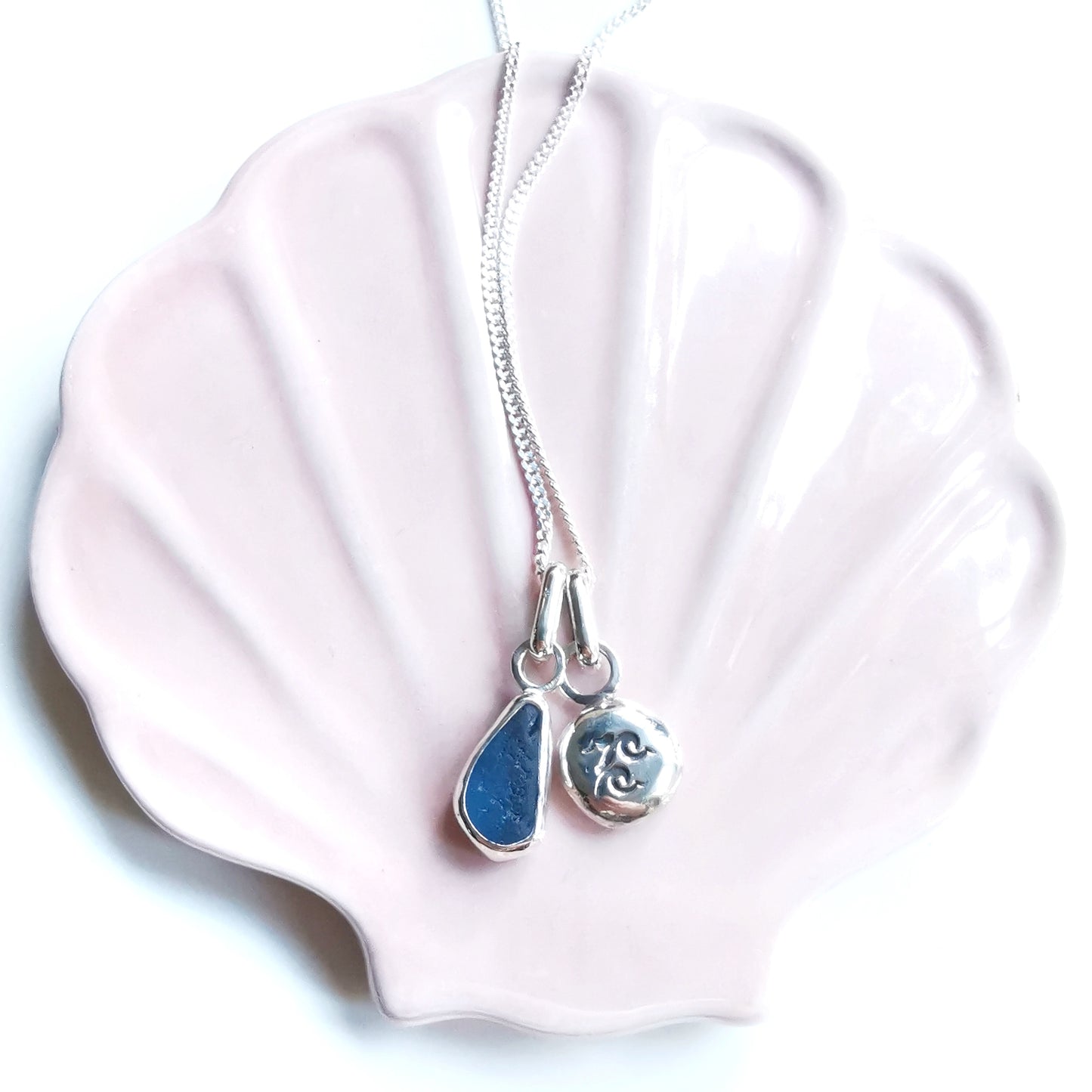 Blue sea glass and silver wave pebble duo of pendants.