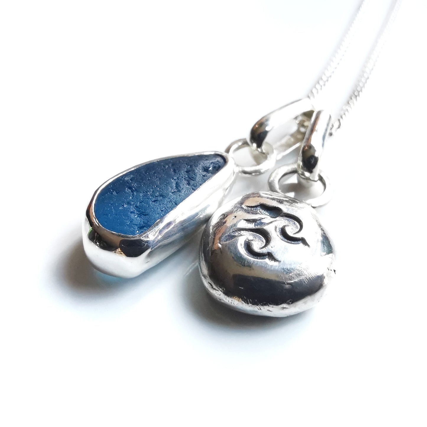 Blue sea glass and silver wave pebble duo of pendants.