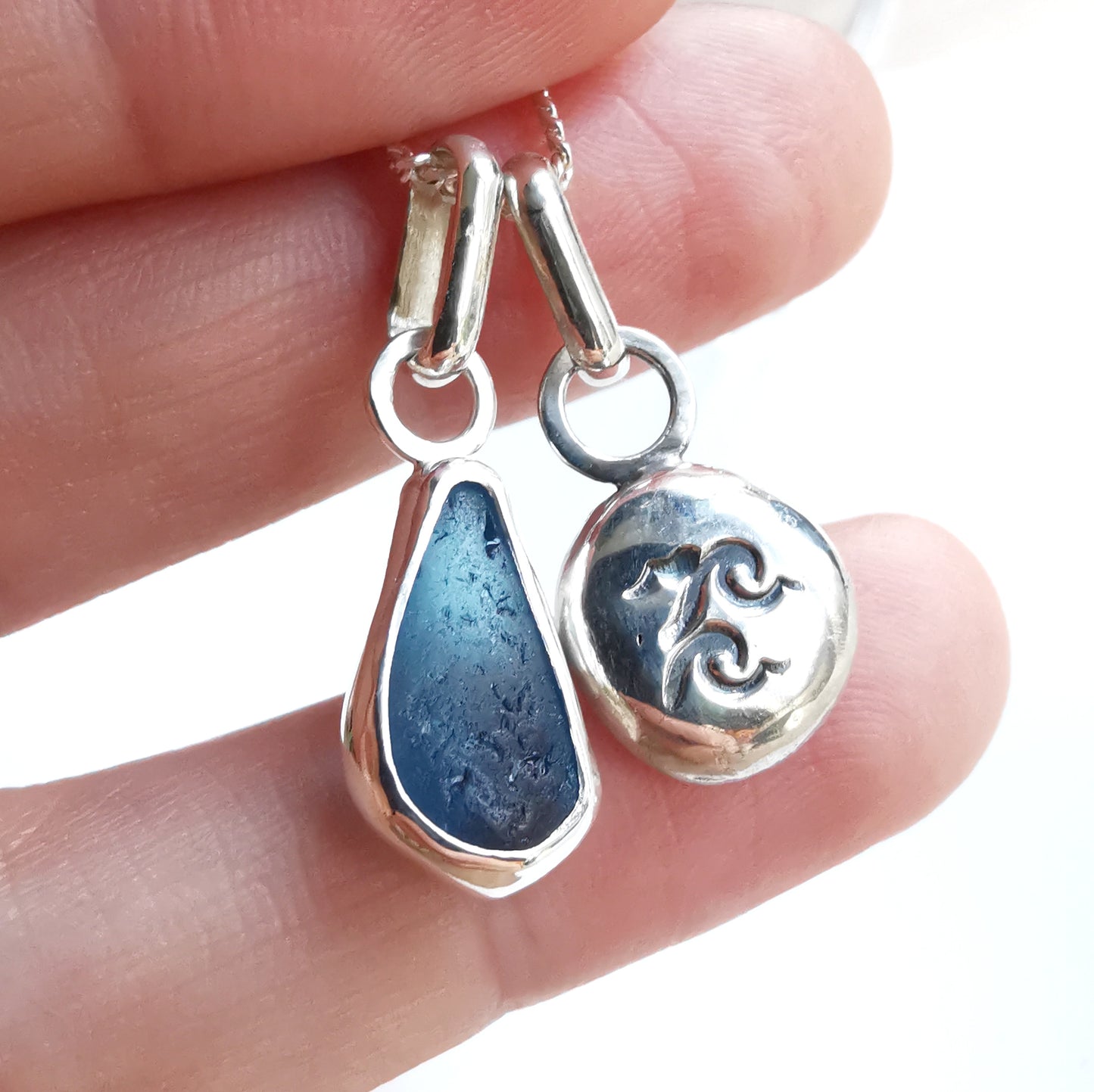 Blue sea glass and silver wave pebble duo of pendants.