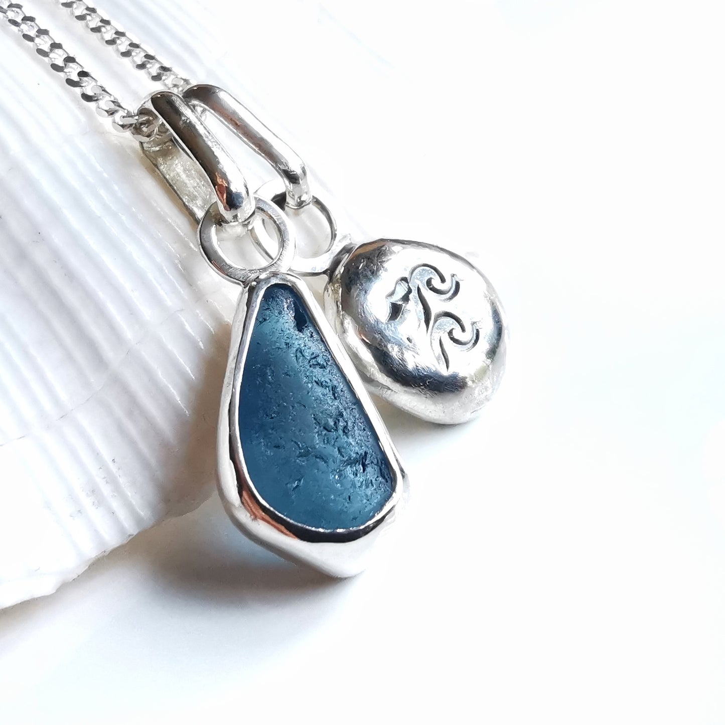 Blue sea glass and silver wave pebble duo of pendants.