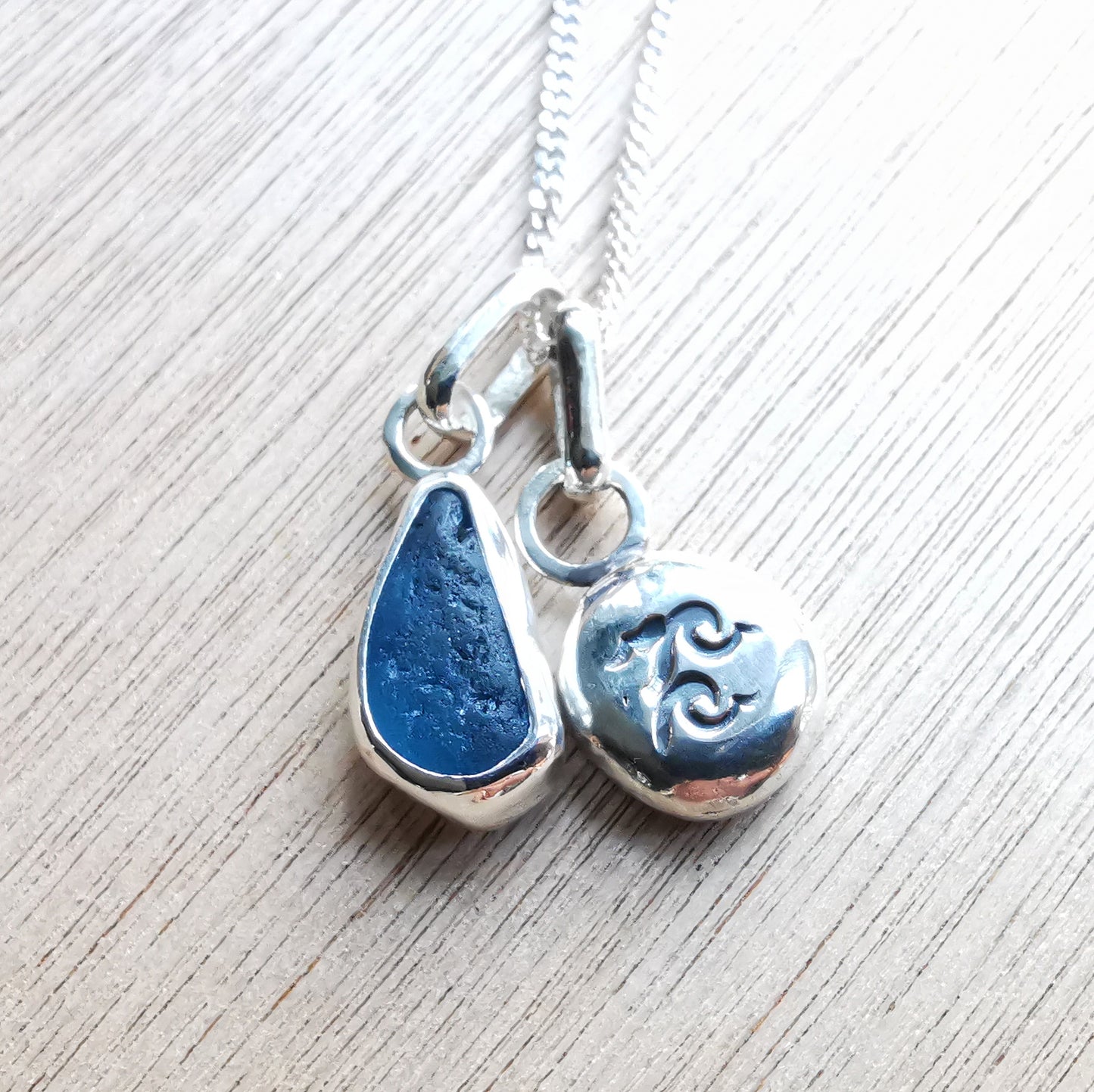 Blue sea glass and silver wave pebble duo of pendants.