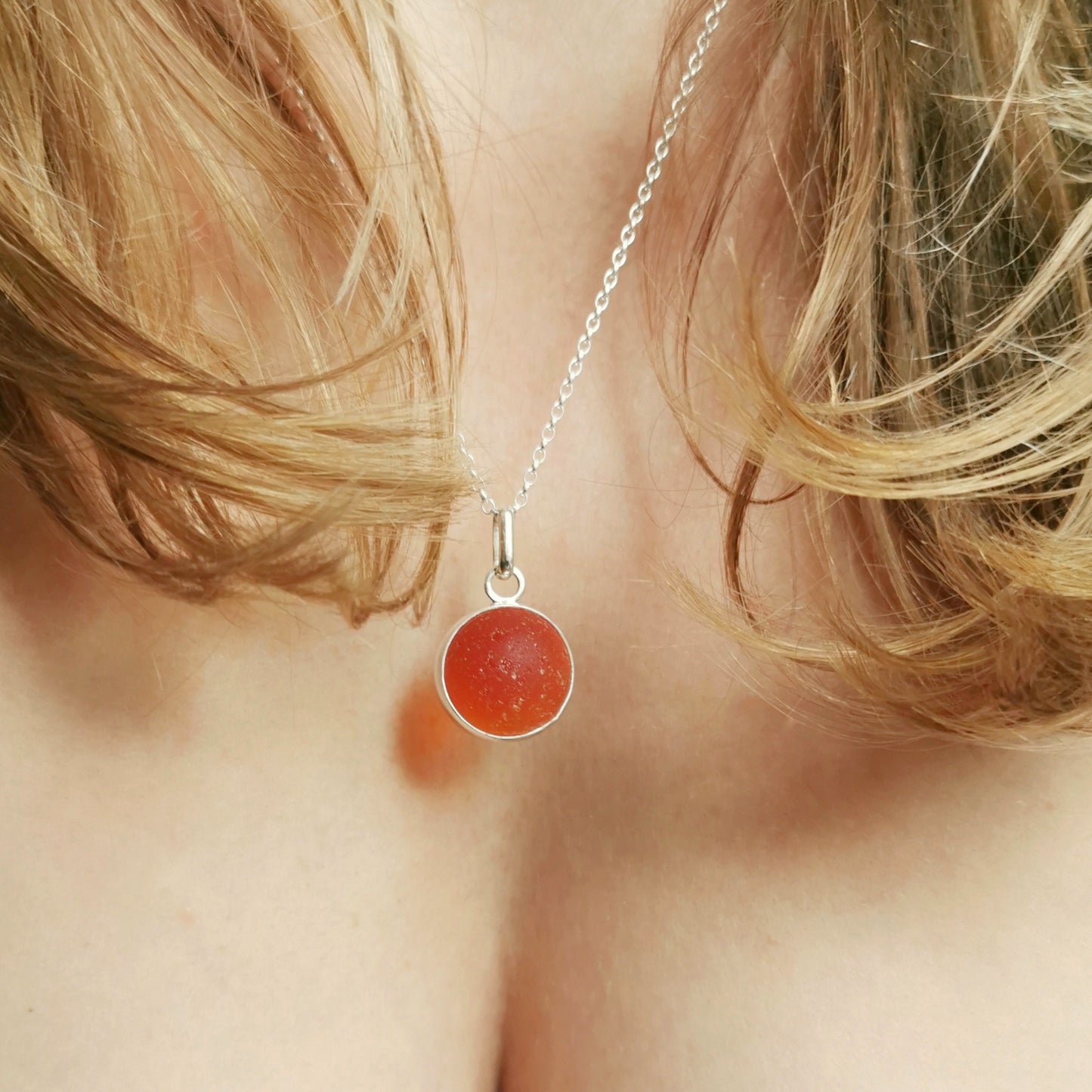 Genuine orange UV sea glass marble & sterling silver pendant.