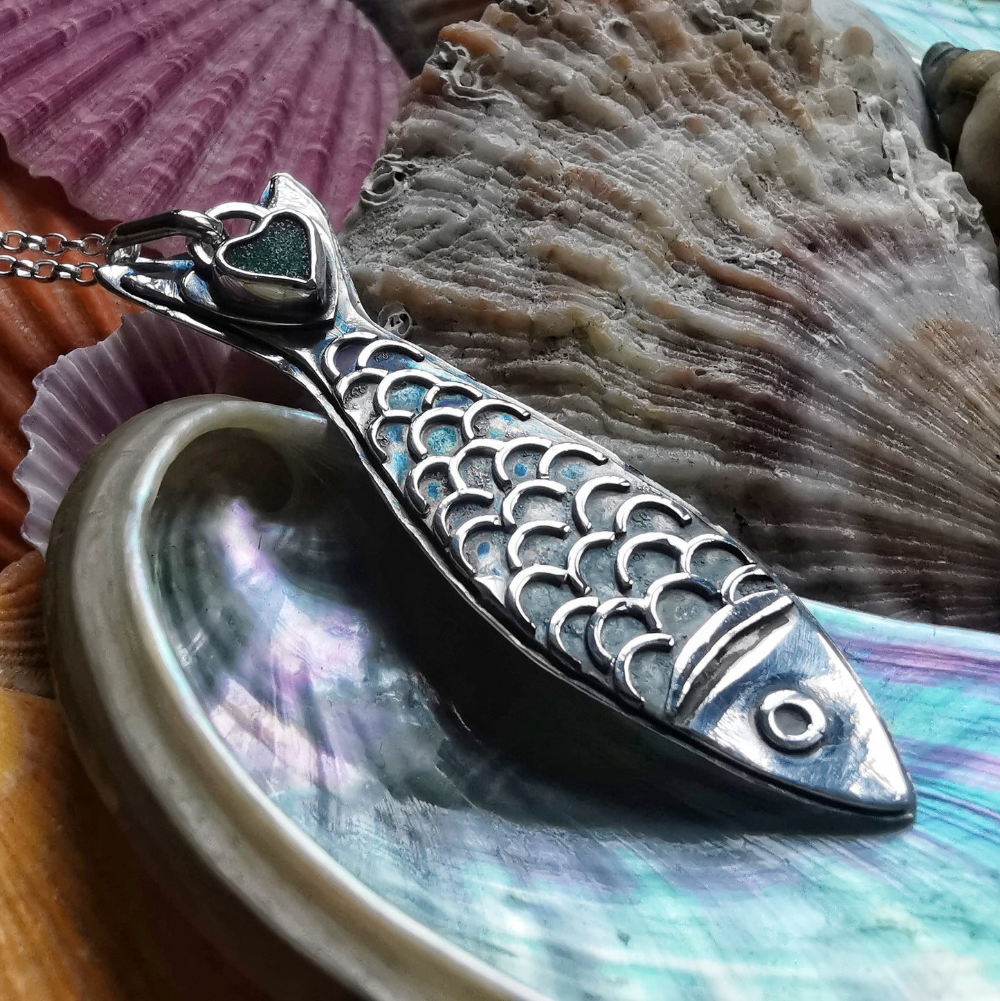 Silver fish pendant with sea glass heart detail.