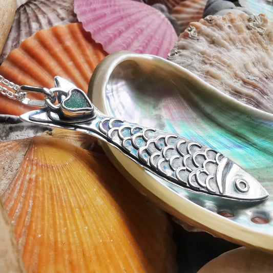 Silver fish pendant with sea glass heart detail.