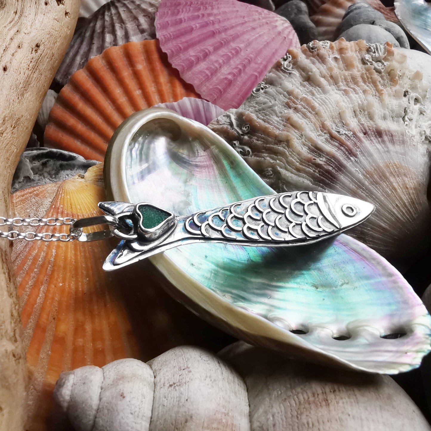 Silver fish pendant with sea glass heart detail.