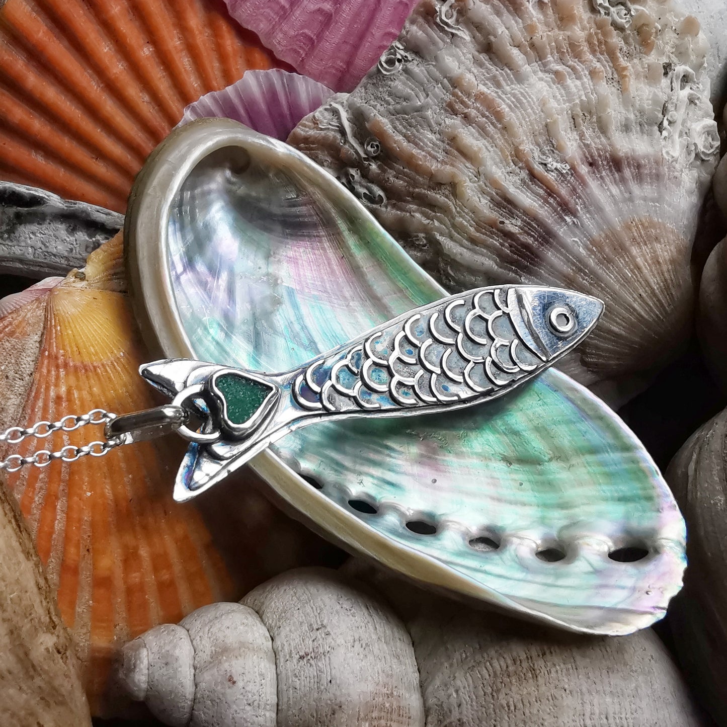 Silver fish pendant with sea glass heart detail.