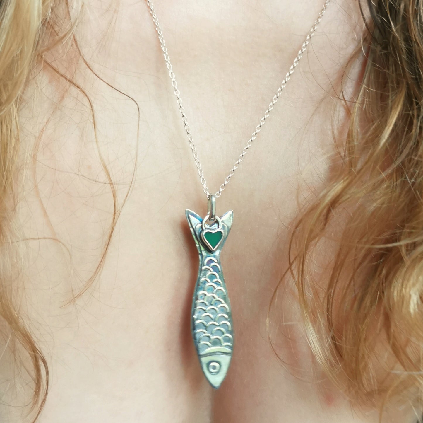 Silver fish pendant with sea glass heart detail.