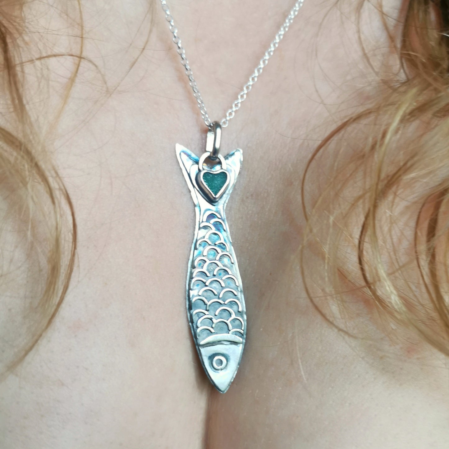 Silver fish pendant with sea glass heart detail.
