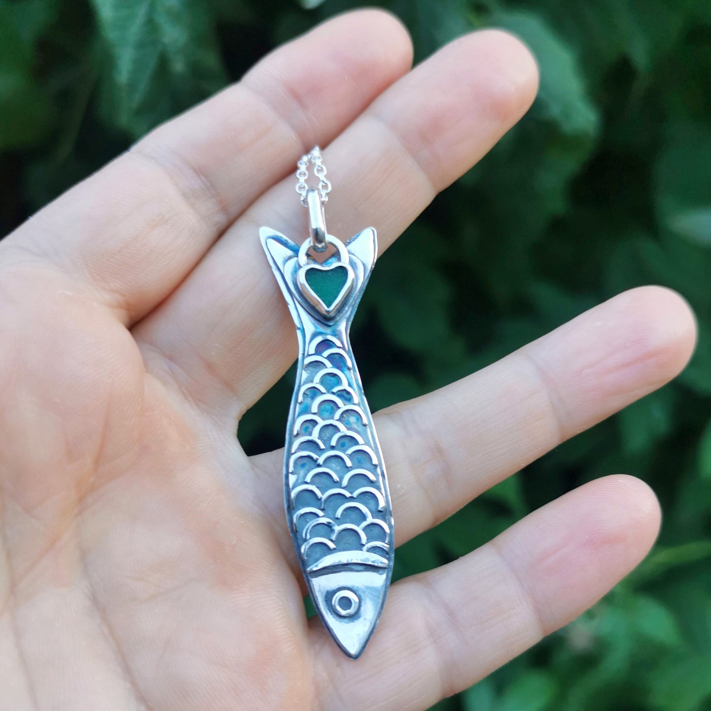 Silver fish pendant with sea glass heart detail.