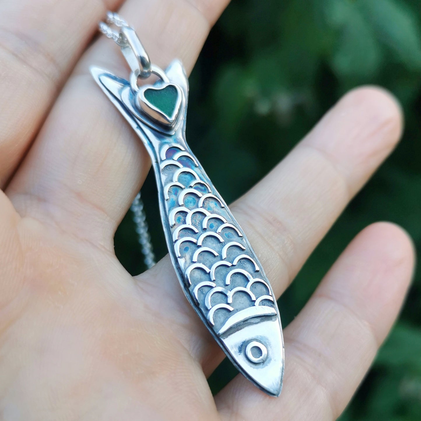 Silver fish pendant with sea glass heart detail.