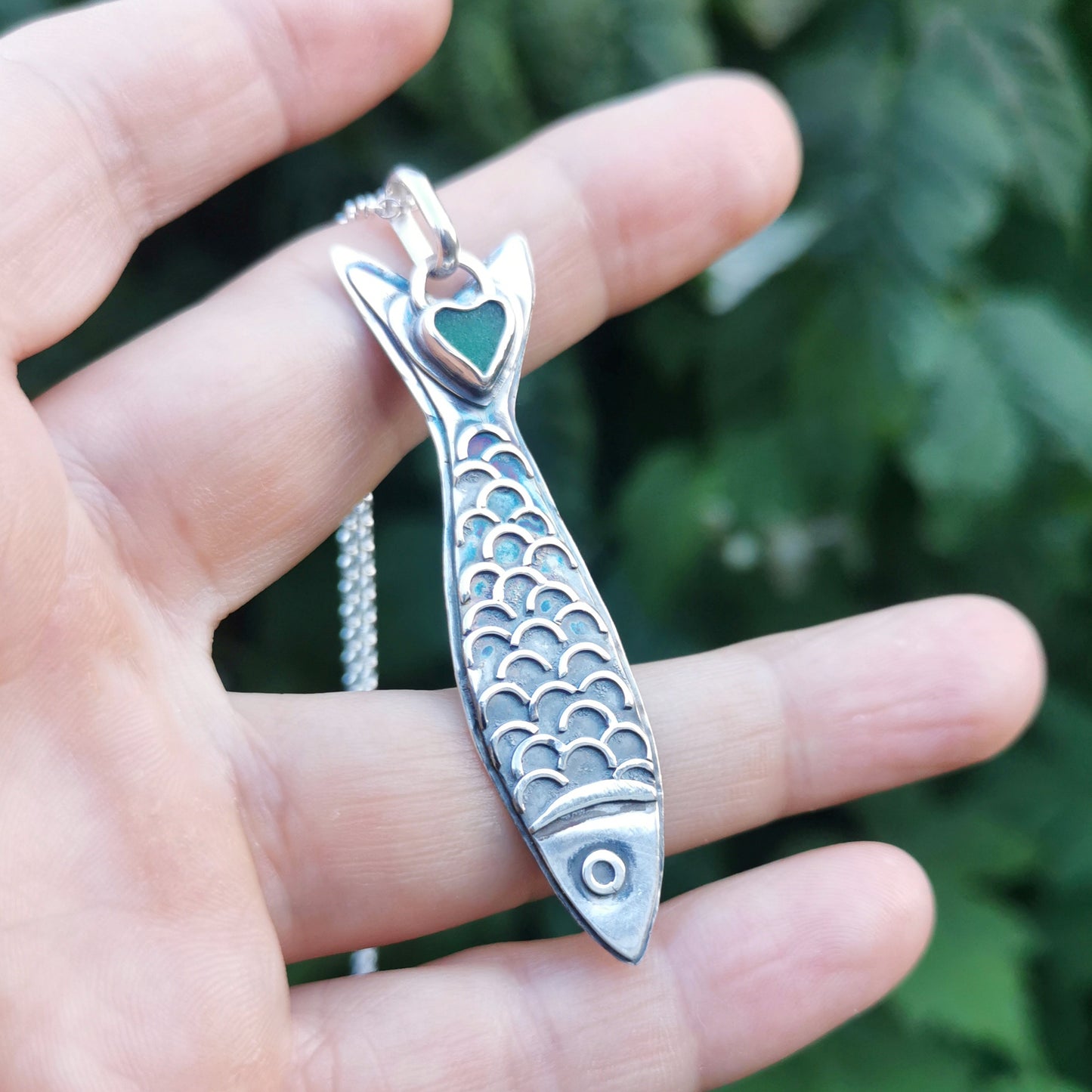Silver fish pendant with sea glass heart detail.